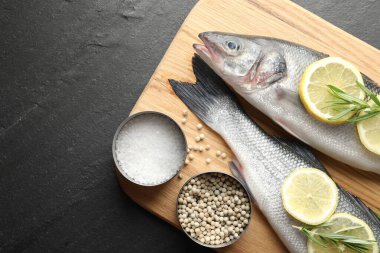 Siyah masadaki baharatlı taze çiğ deniz kabuğu balığı, üst görünüm ve metin için yer. Deniz ürünleri lezzetleri.