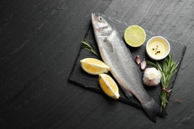 Siyah masadaki baharatlı taze çiğ deniz kabuğu balığı, üst görünüm ve metin için yer. Deniz ürünleri lezzetleri.