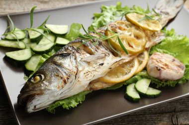 Ahşap masada sebze ve limonla servis edilen kızarmış deniz kabuğu balığı, yakın plan. Ev yapımı deniz ürünleri yemeği.