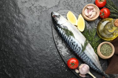 Deniz ürünleri lezzetleri. Taze çiğ uskumru ve baharatlar siyah masada, düz yerde. Metin için boşluk