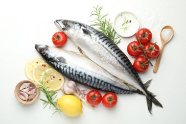 Taze çiğ uskumrular ve baharatlar beyaz masada, düz yerde. Deniz ürünleri lezzetleri.