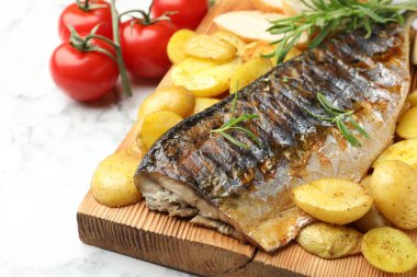 Biberiyeli kızarmış uskumru ve beyaz mermer masada sebzeler, yakın plan. Ev yapımı deniz ürünleri yemeği.