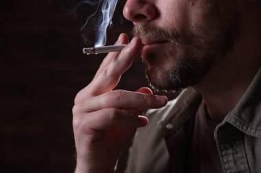 Arka planda sigara içen adam, yakın plan.