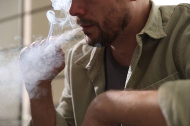 Arka planda sigara içen adam, yakın plan.