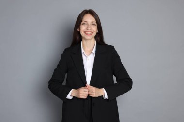 Gri arka planda takım elbiseli mutlu kadın