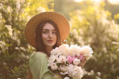 Güneşli bir günde parkta şakayık demeti olan güzel bir kadın.