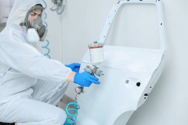 Kaportacının kapısını boyayan bir işçi.