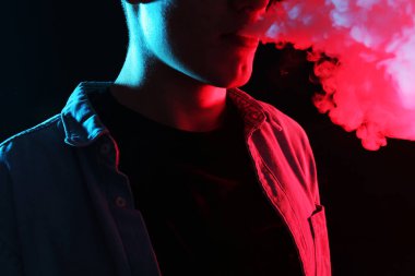 Siyah arka planda neon lambalarda elektronik sigara içen adam, yakın plan