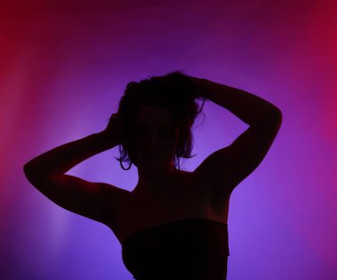 Renkli arka planda neon ışıklarla poz veren kadın silueti