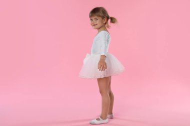 Pembe arka planda dans eden tatlı küçük kız.