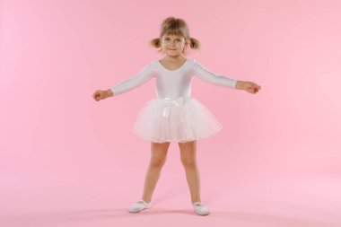 Pembe arka planda dans eden tatlı küçük kız.