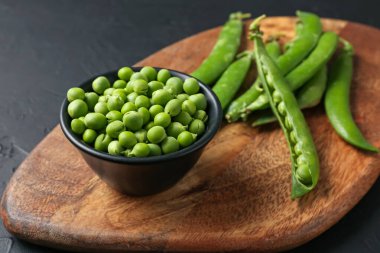 Taze taze bezelyeler siyah masada, yakın plan.