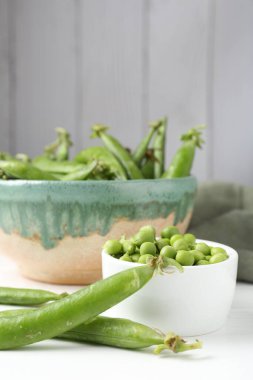 Taze taze bezelyeler beyaz ahşap masada, yakın plan.