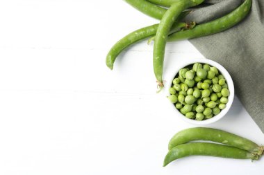 Taze taze bezelyeler beyaz ahşap masada, düz yerde. Metin için boşluk