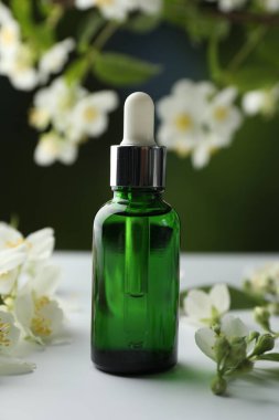 Temel yağ ve yasemin çiçekleri beyaz masada bulanık arka planda, yakın plan