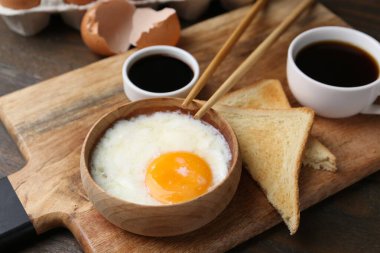 Kavanozda yarı haşlanmış yumurta, soya sosu, yemek çubukları, kahve ve ahşap masada kızarmış ekmek, yakın plan. Geleneksel Asya kahvaltısı