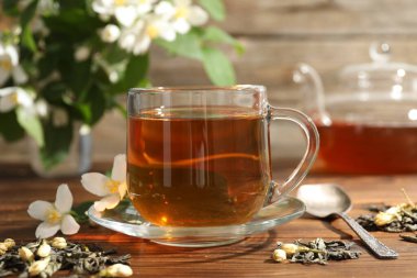 Aromatik yasemin çayı cam bardakta, bira ve çiçekler ahşap masada, yakın plan