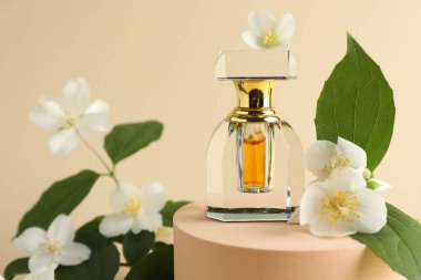 Bir şişe parfüm ve bej arka planda yasemin çiçekleri, yakın plan.