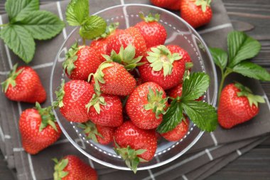 Taze olgun çilekler ve yapraklar siyah ahşap masada, düz yatıyordu.