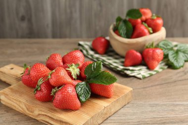 Ahşap masada lezzetli olgun çilekler ve yeşil yapraklar, yakın plan. Metin için boşluk