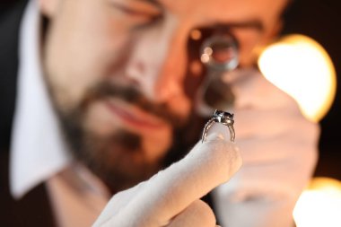 Kapalı alanda lüks yüzük değerlendirmesi yapan, seçici odaklı bir eksper.