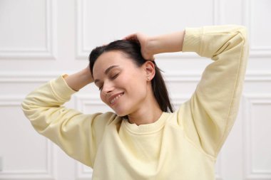 Uyum. Evdeki beyaz duvarın yanında uzanan gülümseyen kadın.