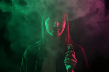 Siyah arka planda neon ışıkları altında elektronik sigara içen kadın
