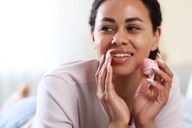 Arka planda dudak kremi olan gülümseyen kadın, yakın plan.