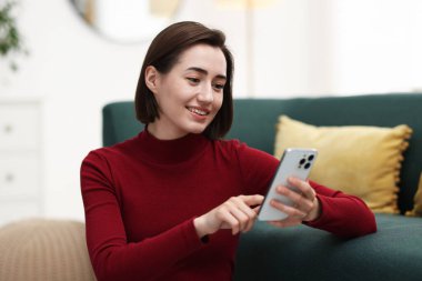 Evde modern akıllı telefon kullanan güzel bir kadın.