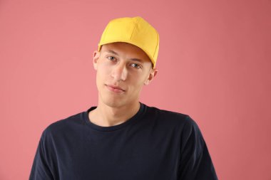 Pembe arka planda şık bir beyzbol şapkası takan genç adam.