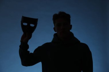 Anonimlik. Mavi arka planda maskeli bir adamın silueti