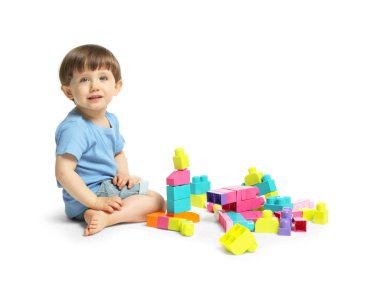 Beyaz arka planda tuğlalarla oynayan sevimli küçük çocuk.