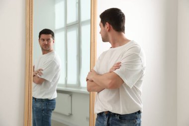 Yakışıklı adam aynada kendine bakıyor.