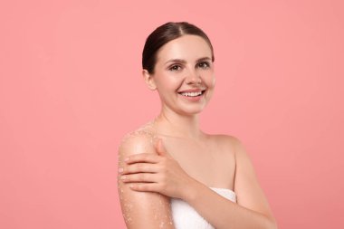 Gülümseyen kadın vücudunu pembe arka plana sürterek koluna sürüyordu.