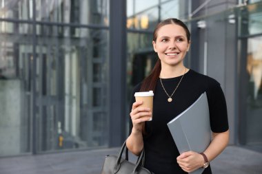 Ofis binasının yakınında kahve ve klasörlü başarılı bir iş kadını. Metin için boşluk