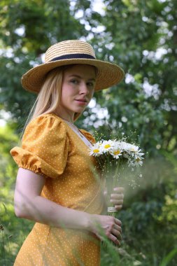 Ormanda bir buket kır çiçeğiyle güzel bir kadın