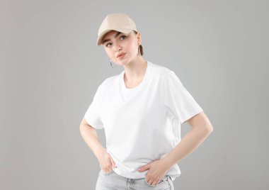 Gri arka planda şık beyzbol şapkalı güzel bir kadın.