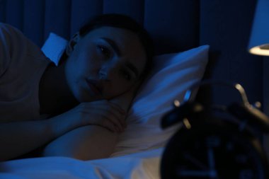 Evde yatakta uykusuzluk çeken hayal kırıklığına uğramış bir kadın.