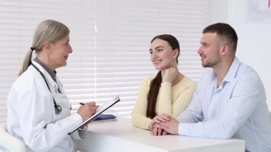 Tüp bebek (tüp bebek). Mutlu çift, üreme kliniğinde doktorla görüşüyor.
