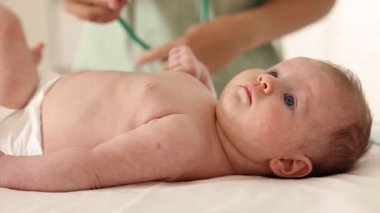 Doktor hastanede steteskopla şirin bebeği muayene ediyor.