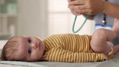 Doktor hastanede steteskopla şirin bebeği muayene ediyor.