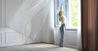 Uyum. Evdeki açık pencerenin yanında uzanan gülümseyen kadın.