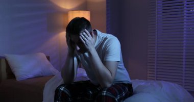 Yatakta uykusuzluk çeken sinirli bir adam.