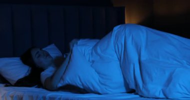 Evde yatakta uykusuzluk çeken hayal kırıklığına uğramış bir kadın.