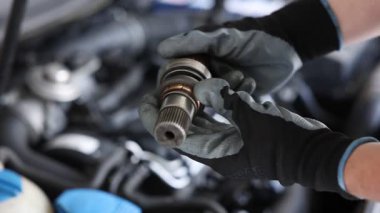 Otomobil parçası. Kaputun açık kaputu yakınında sürücü mili olan profesyonel bir tamirci, yakın plan.