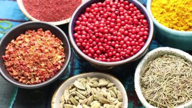 Mavi masa örtüsündeki farklı aromatik baharatlar, dönüyor. Yakın çekim.