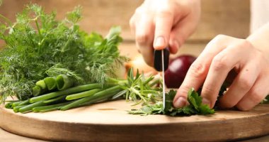Masada kişniş ve diğer farklı otları kesen kadın, yakın plan.