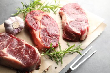 Gri masa üzerinde çiğ et, baharat ve çatal parçaları.