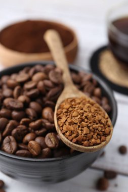 Kavrulmuş fasulye ve granüle edilmiş kahve beyaz ahşap masada, yakın plan.