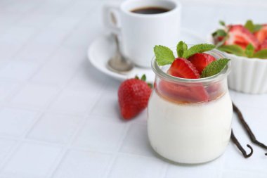 Karamelli panna cotta, çilek, nane, vanilya kabuğu ve beyaz fayanslı masada kahve, yakın plan. Metin için boşluk